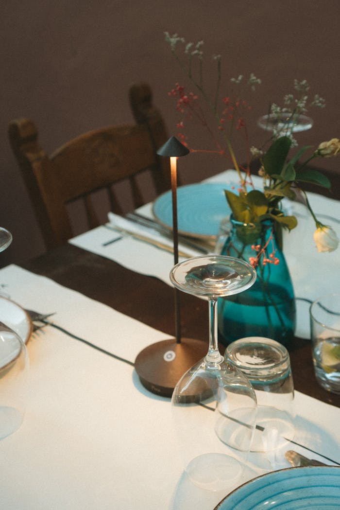 Stylish dinner table setting with wine glasses, candle, and floral decor.